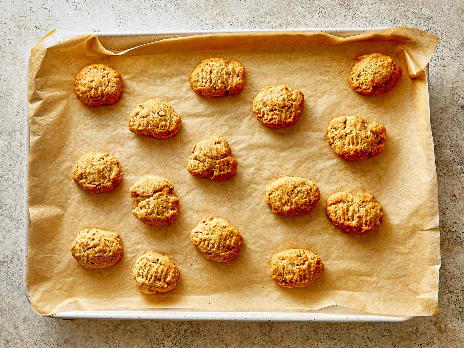 A baking sheet with an arrangement of baked cookies on parchment paper