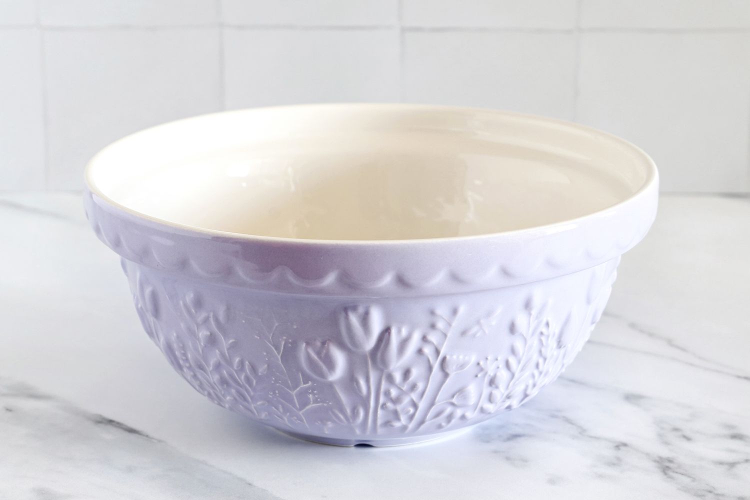 A Mason Cash mixing bowl with a floral embossed pattern on a marble countertop