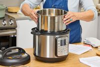 A person removes the inner pot from the Instant Pot Duo Plus 6-Quart 9-in-1 Pressure Cooker