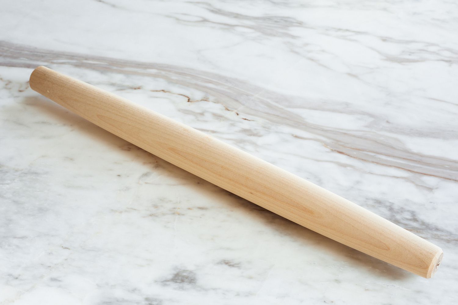 a tapered wooden rolling pin on a marble surface