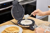 A person pours batter into the Cuisinart WMR-CANAS Round Classic Waffle Maker