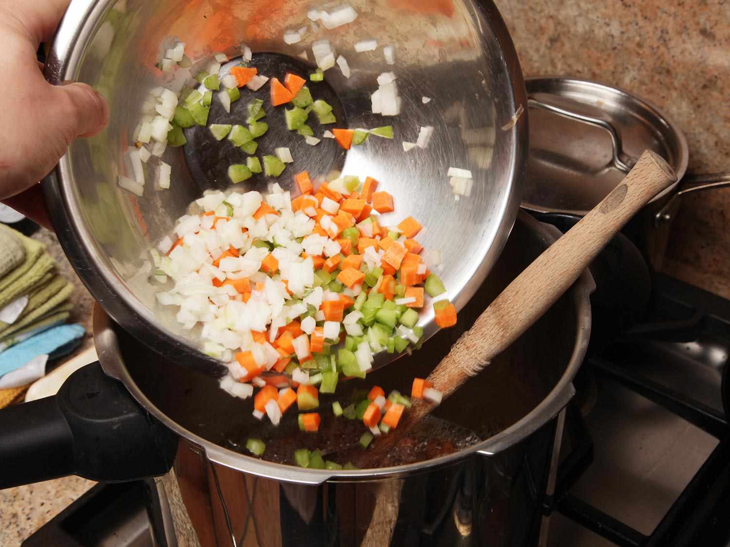 A bowl full of finely chopped onion, carrot, and celery is transferred to the pressure cooker.