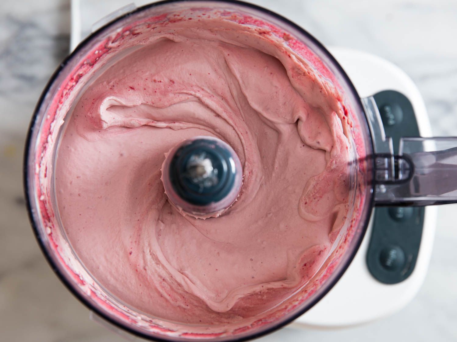 Overhead shot of raspberry whipped cream in a food processor.