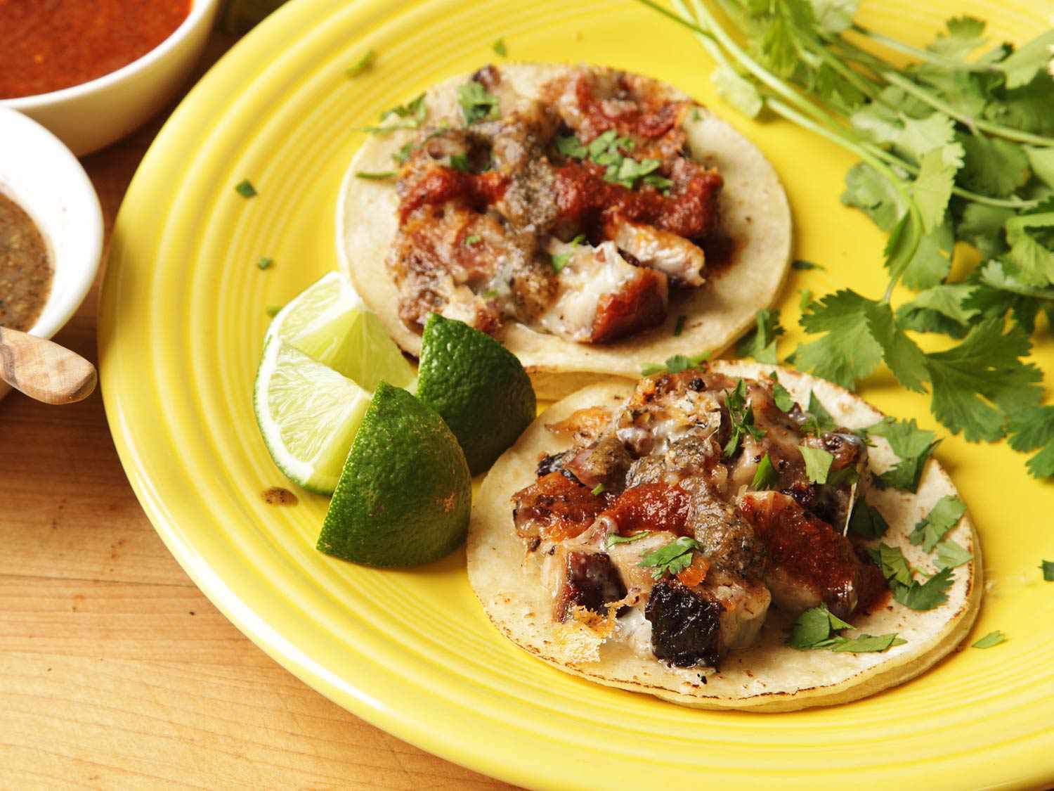 Tacos de castacan on a yellow plate with lime and cilantro
