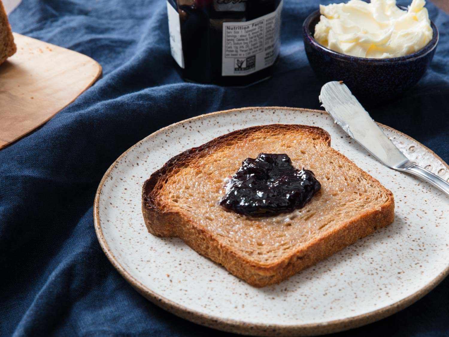 A slice of whole wheat bread topped with butter and jam.