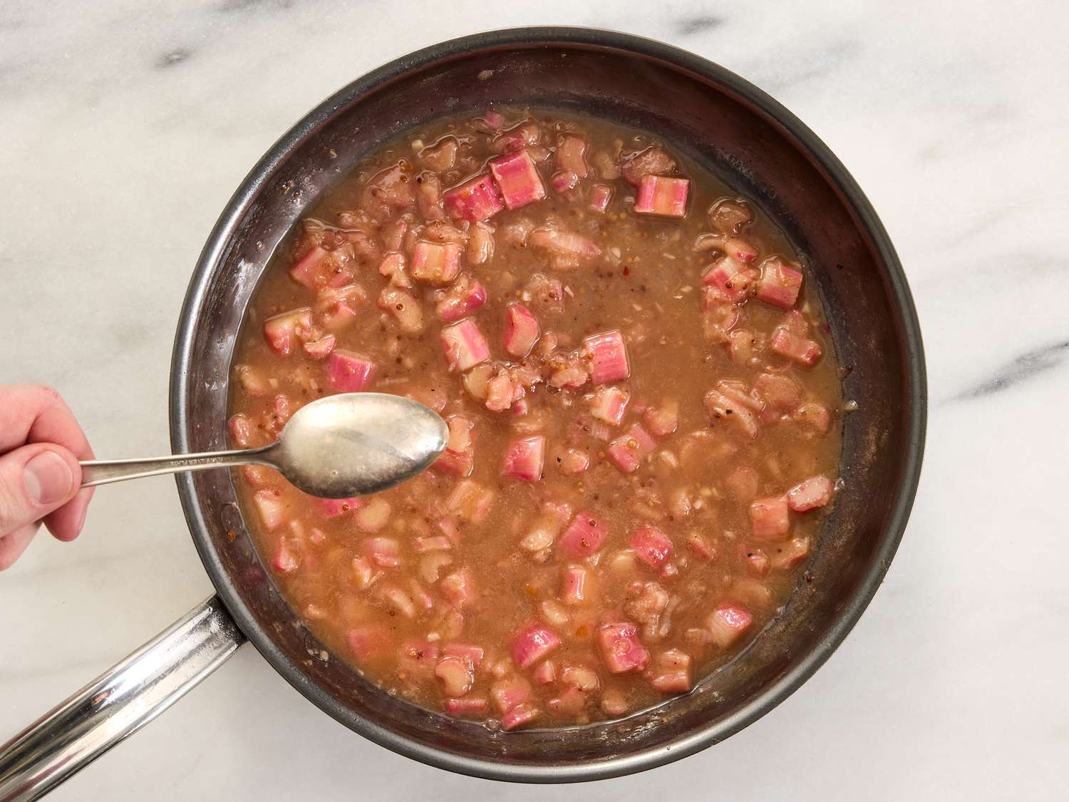 Rhubarb sauce in a pan, mixed with a spoon 