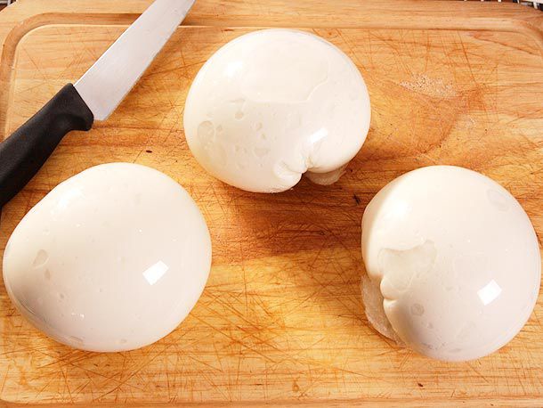 Three balls of mozzarella on a cutting board.