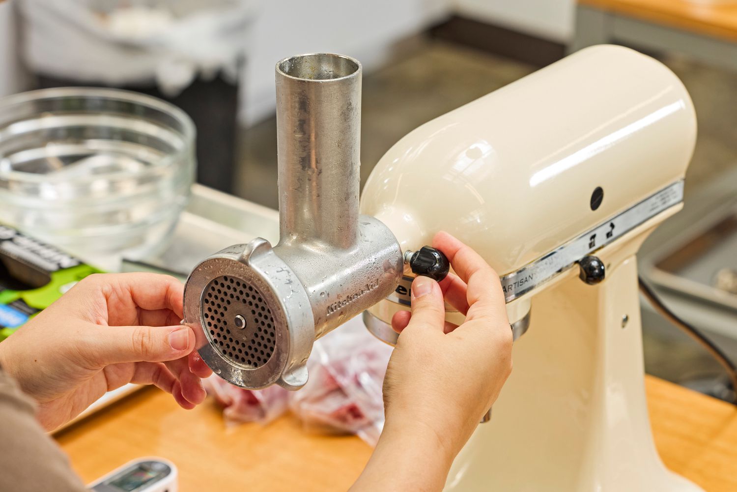 Person turning knob of KitchenAid KSMMGA Metal Food Grinder Attachment