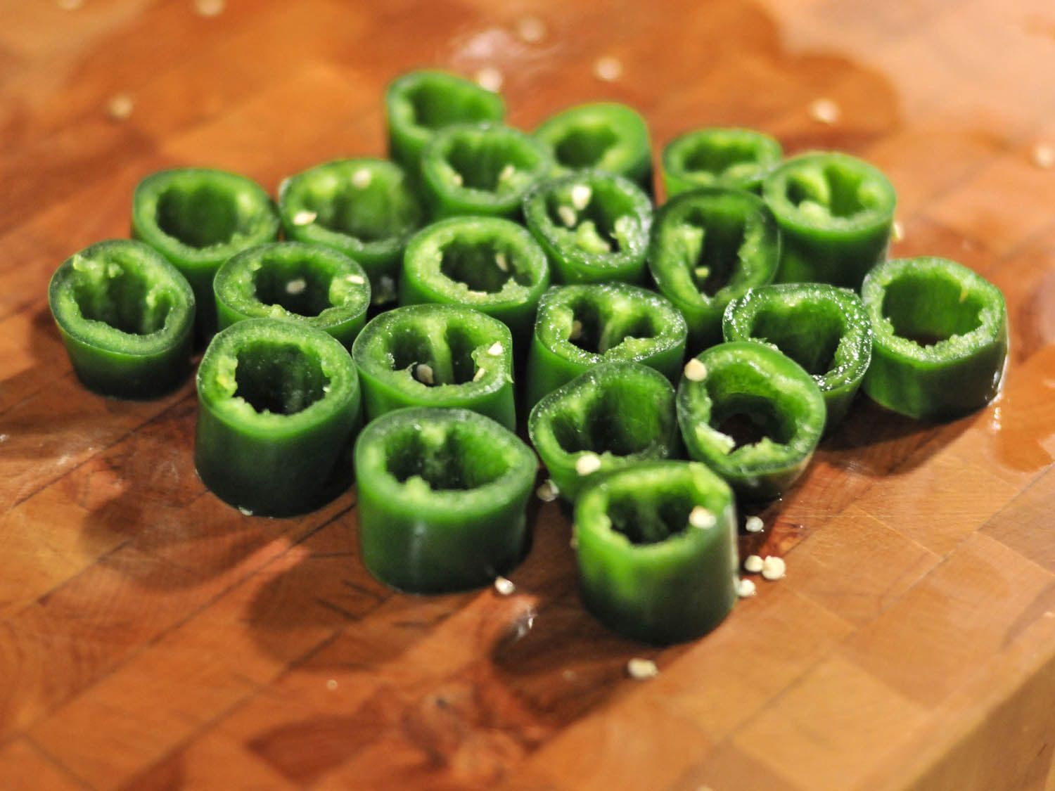 Slices of jalapeño on a cutting board. 