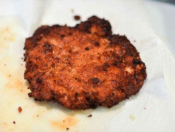 Draining a just-fried chicken schnitzel on paper towels.