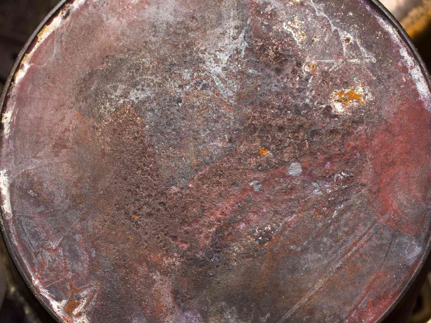 A cast iron skillet with a large amount of pitting and erosion on the backside. 