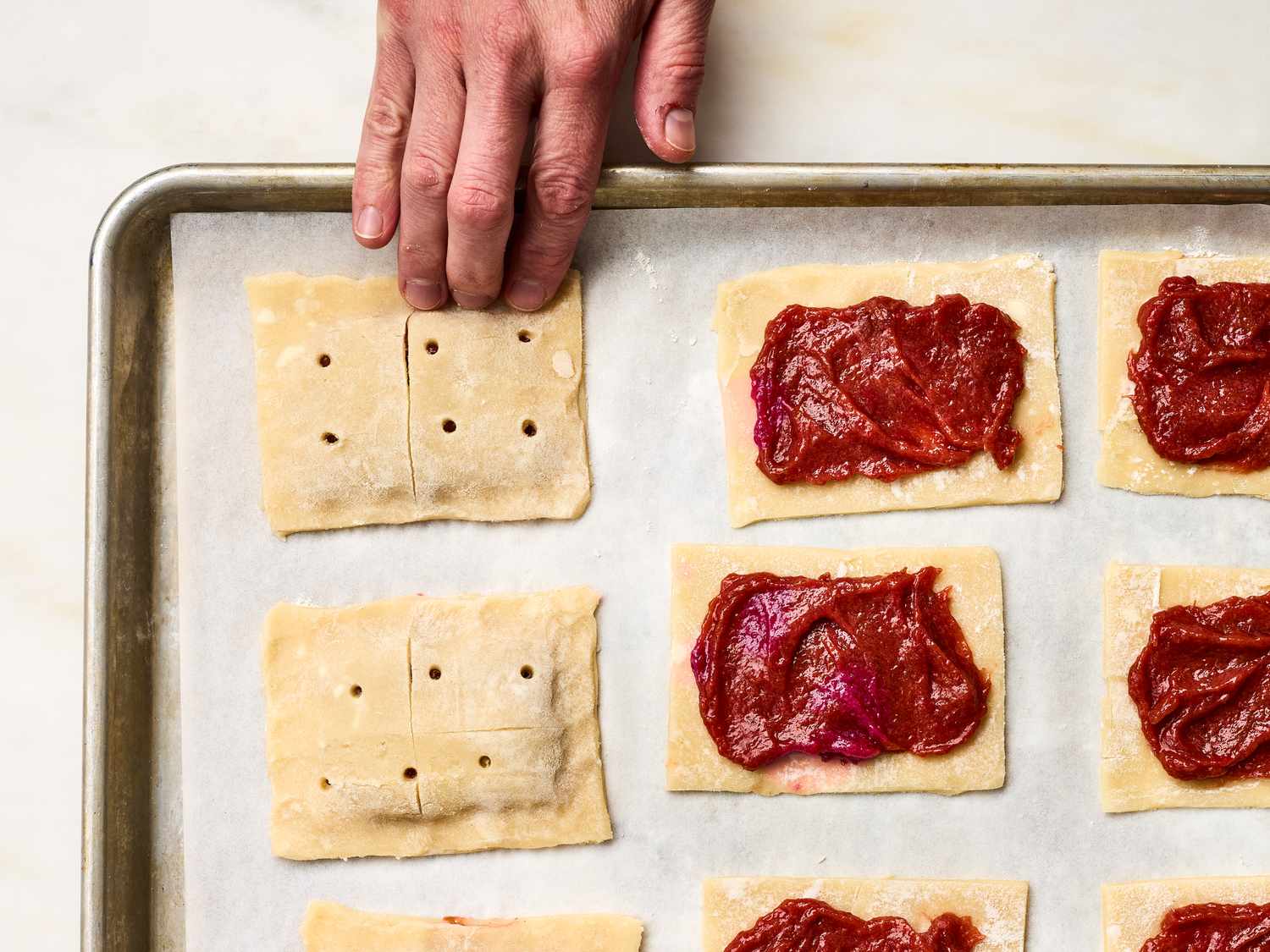 Preparing strawberry rhubarb pastries on a baking sheet