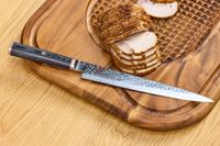 The Miyabi Mizu SG2 9.5 Inch Slicing Knife on a cutting board