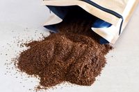 Ground coffee spilling from a paper bag