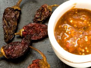 A small bowl of chile morita salsa next to some dried morita chiles. 