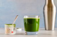 A glass of Ippodo Tea Ummon Matcha next to the container