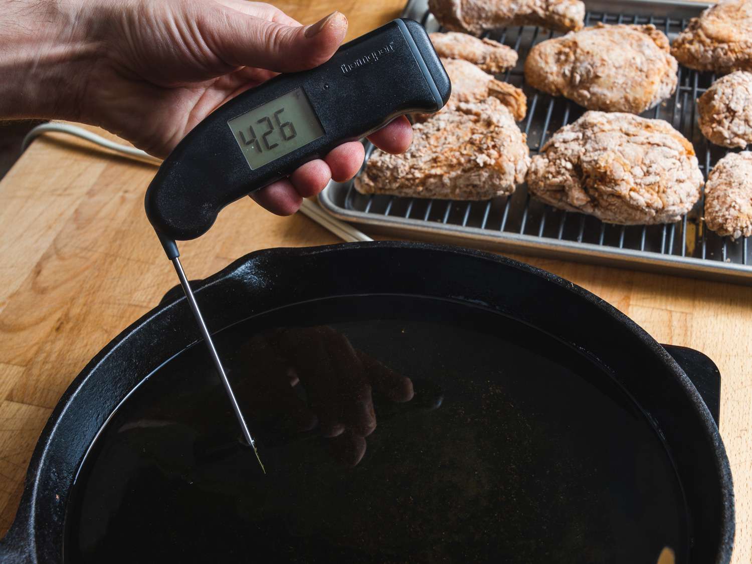 Instant read thermometer in a pot of oil measuring 426 degrees Fahrenheit.