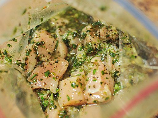 Peeking into the zipper-top bag at the marinating chicken with lots of fresh green herbs.