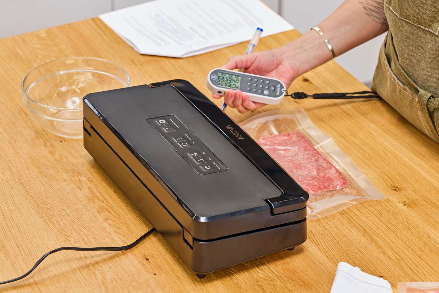A person measures the sound emitted from the Anova Precision Vacuum Sealer Pro while in use