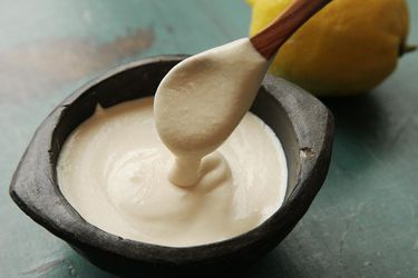 Tahini hummus in a black bowl with a spoonful being taken out 