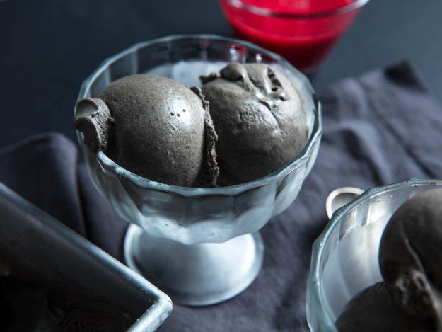 A small glass bowl holding two scoops of black sesame ice cream. 