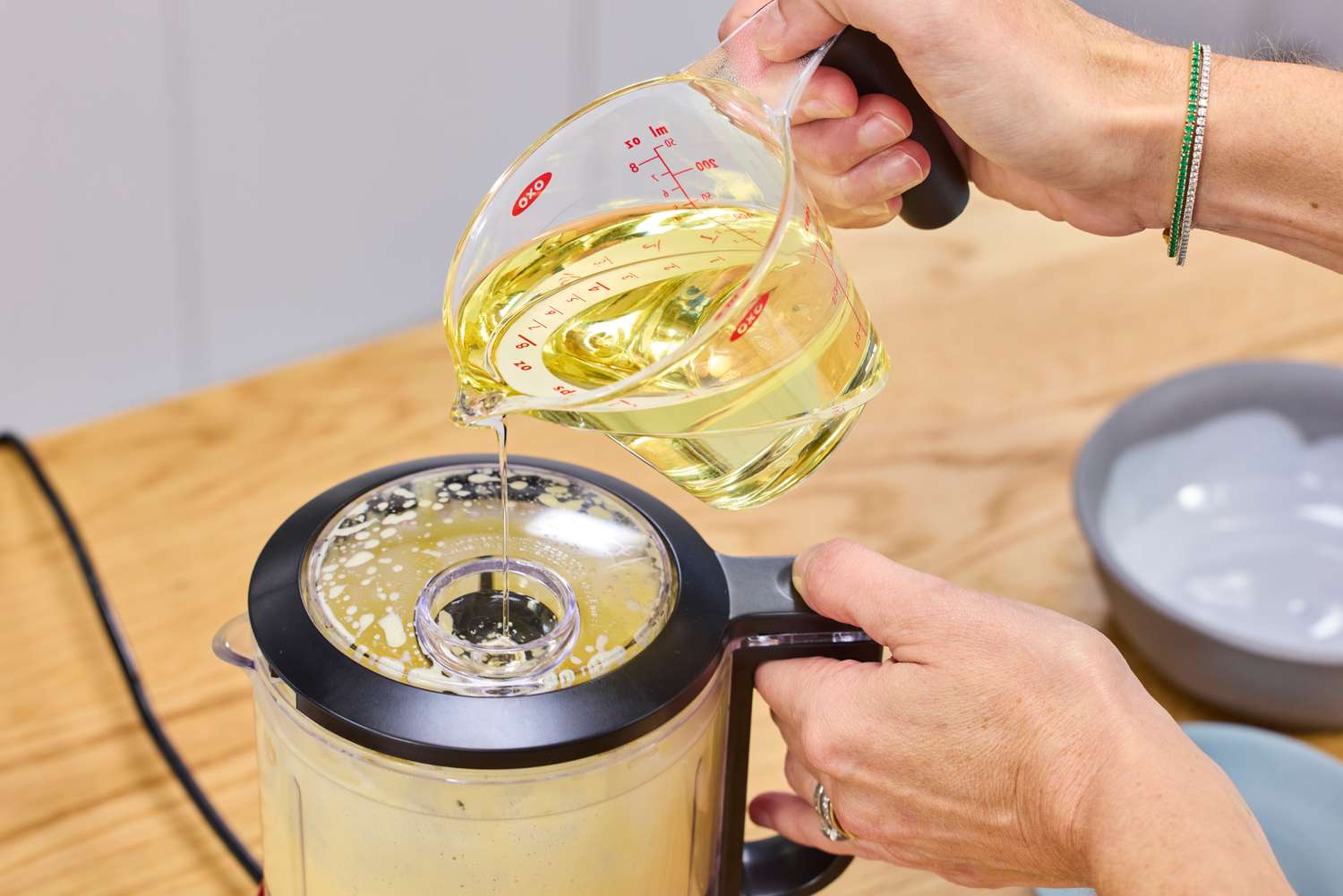 A person pours oil into the KitchenAid 3.5-Cup Food Chopper