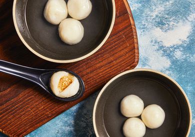 Overhead view of finished Tang Yuan on two bowls with one opened on a soup spoon