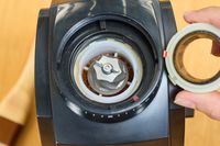A person removes a piece from the Baratza Encore Conical Burr Coffee Grinder