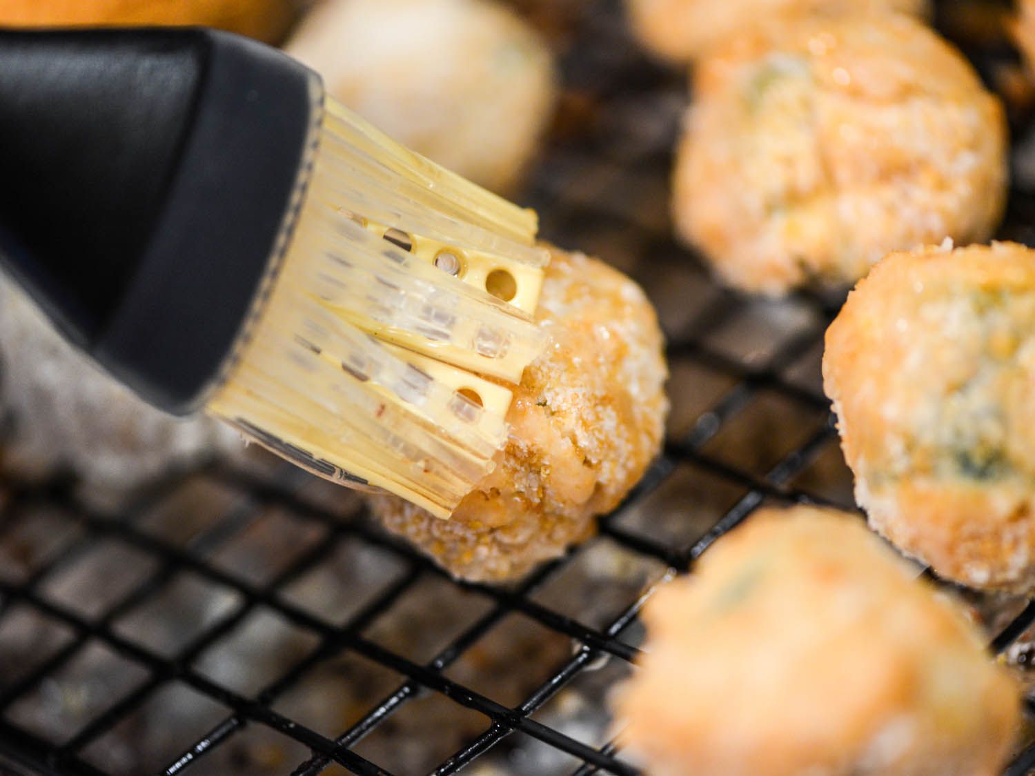 Brushing baked jalapeno poppers with fat. 