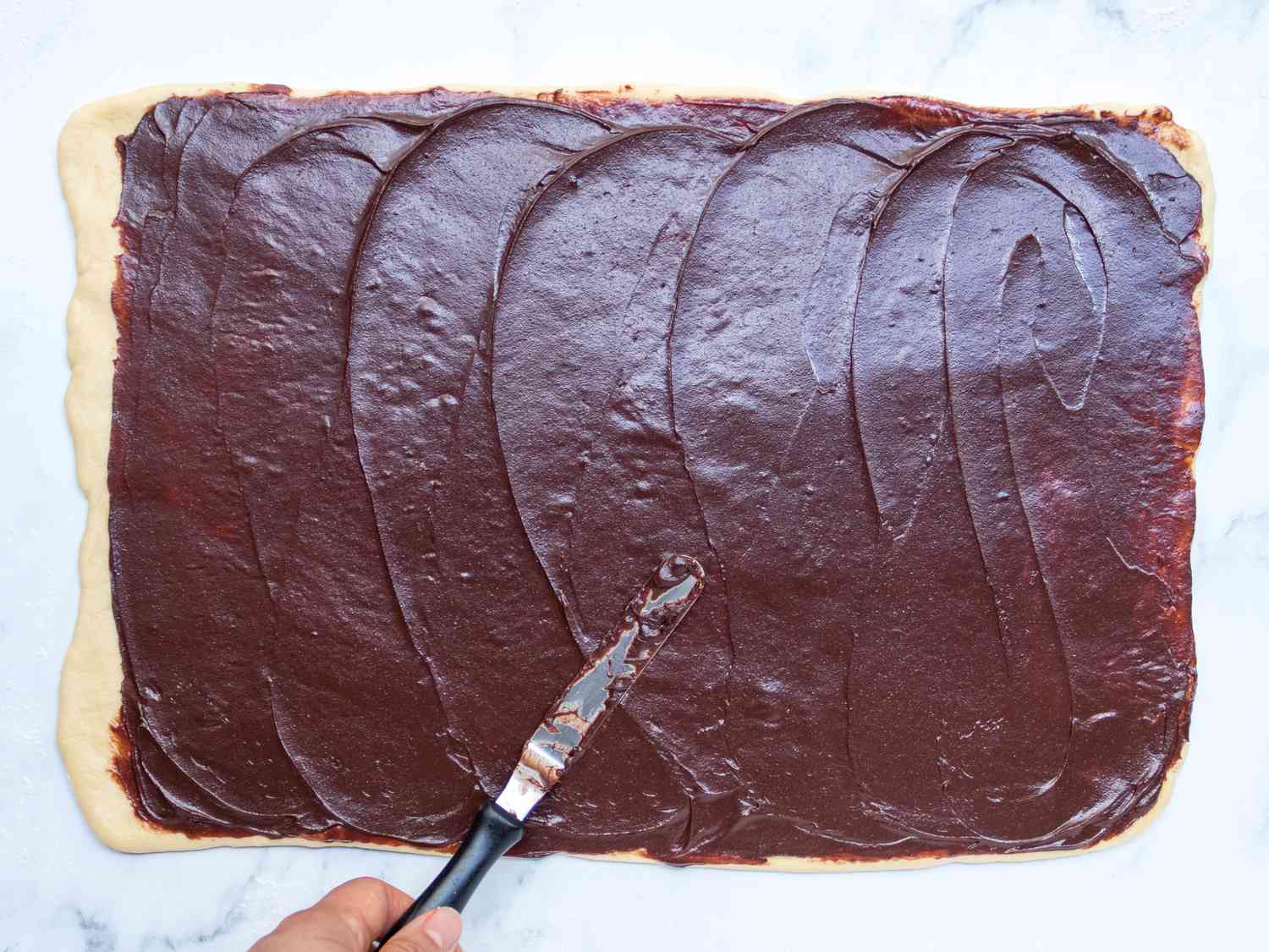 Chocolate filling being spread on top of the dough