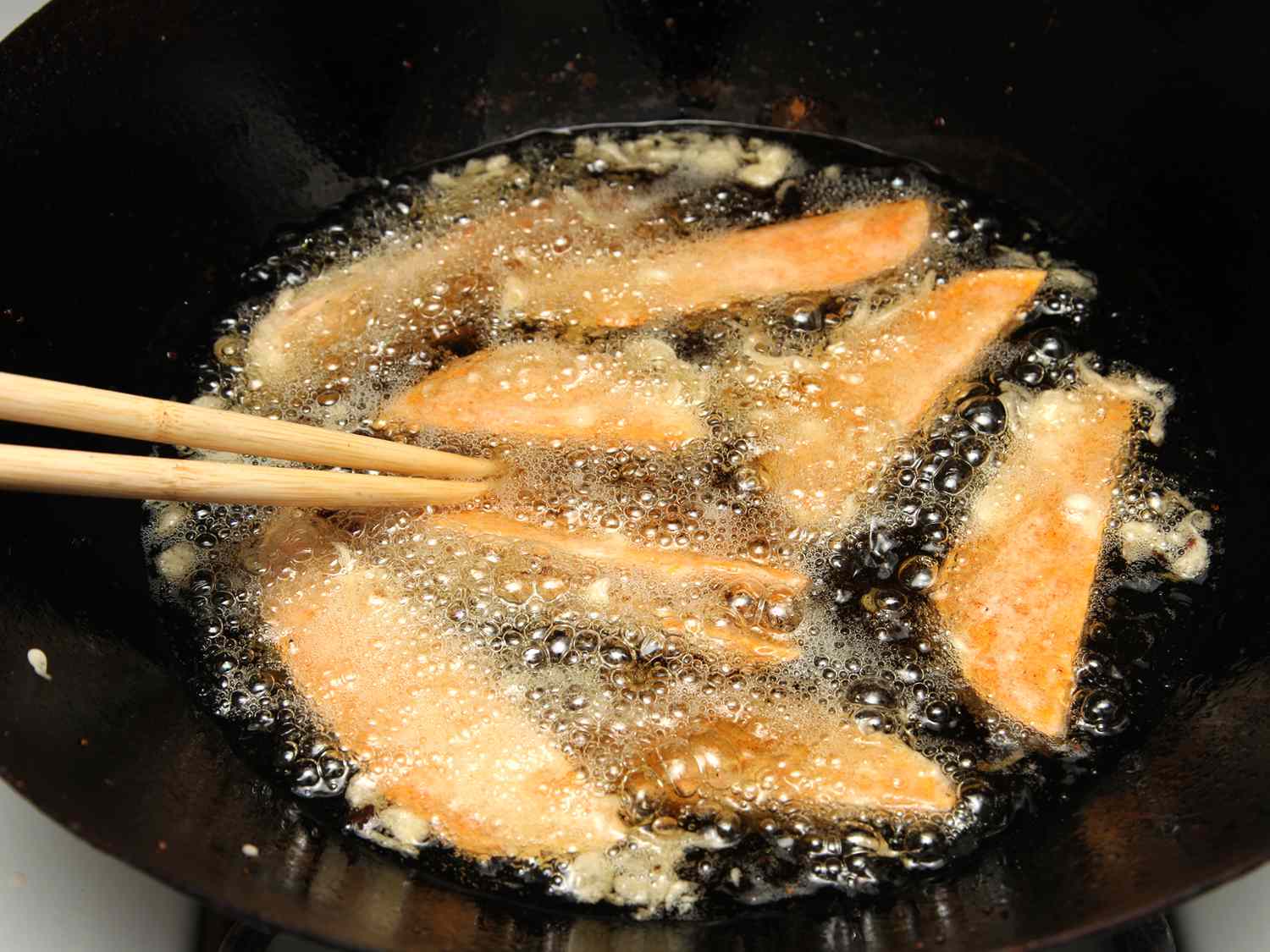 Sweet potato tempura frying in a wok. 