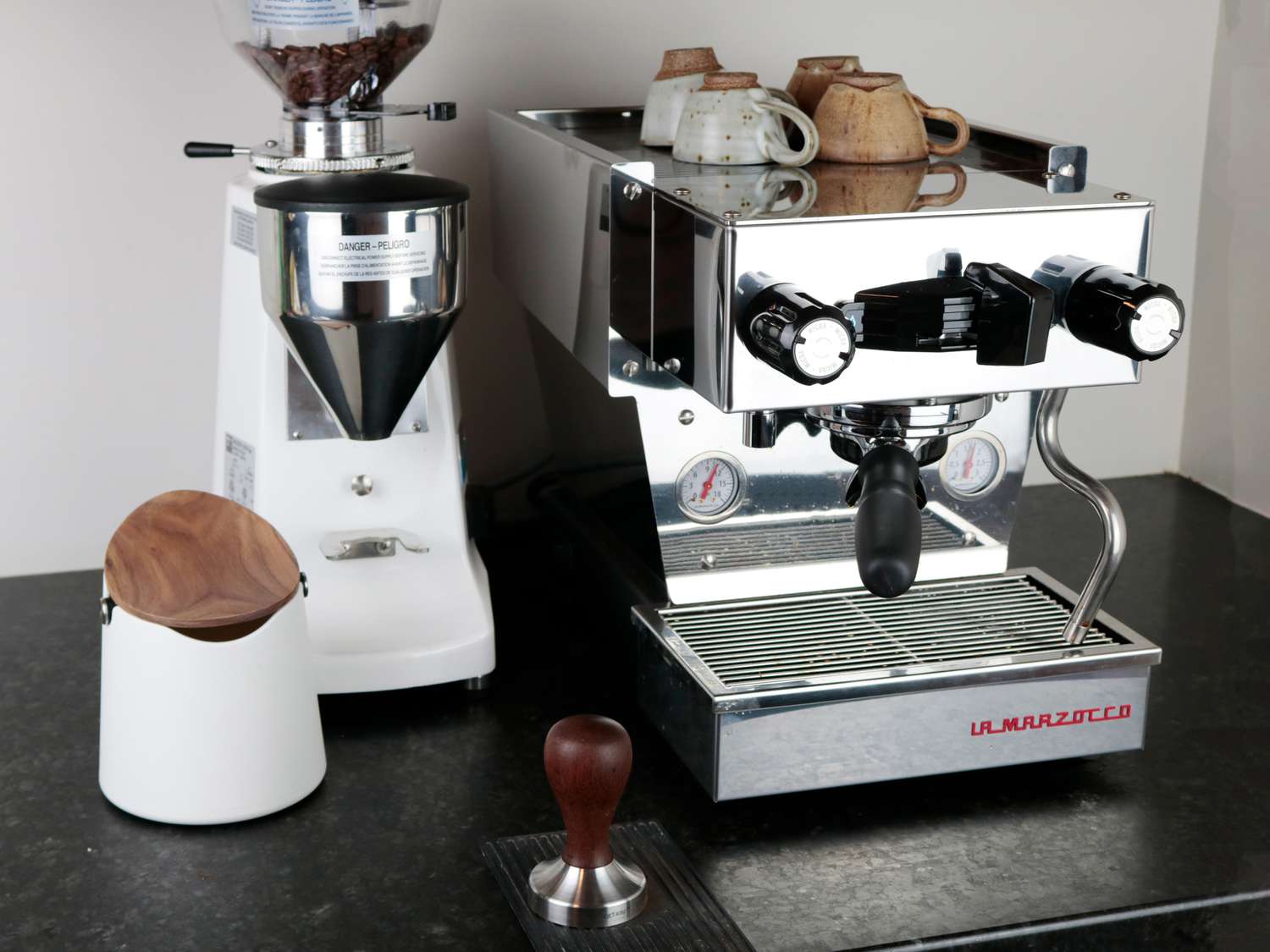 an espresso machine and espresso grinder on a dark counter