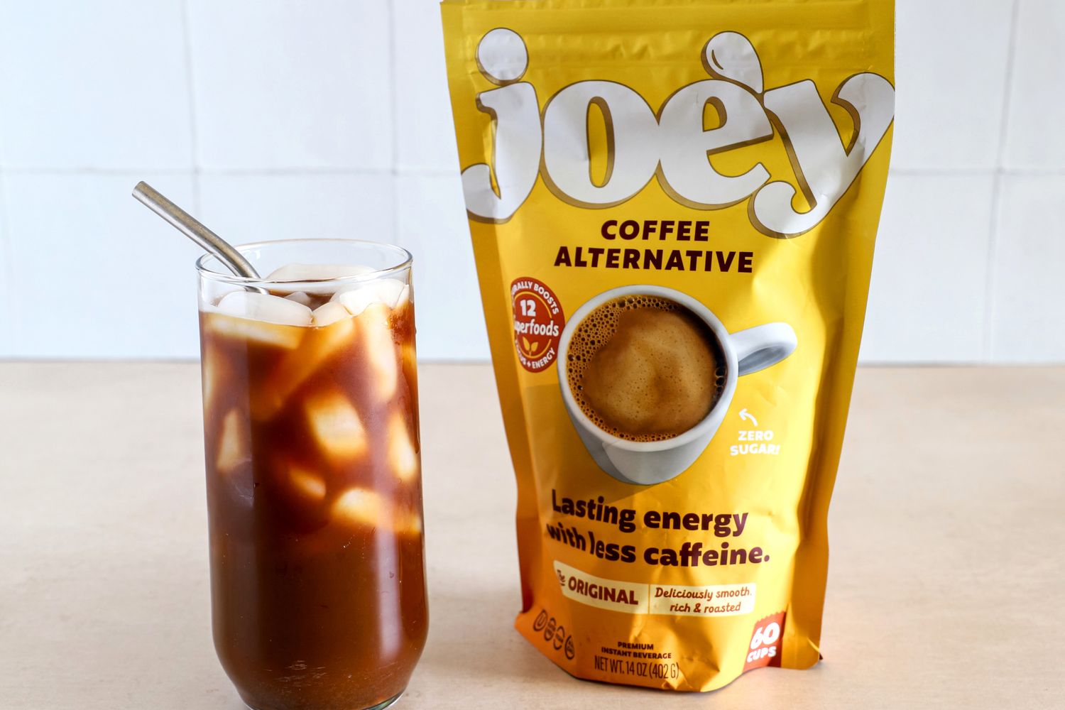 A glass of iced coffee next to Joe'y coffee alternative packaging
