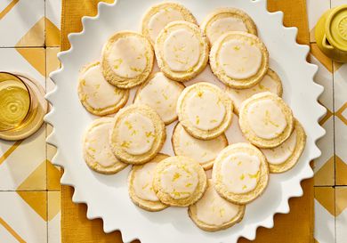 Plate of lemon sugar cookies on a yellow textile on top of yellow and white tiles. 