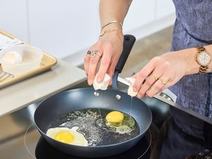 A person cracks eggs into the OXO Obsidian Pre-Seasoned Carbon STeel Pan