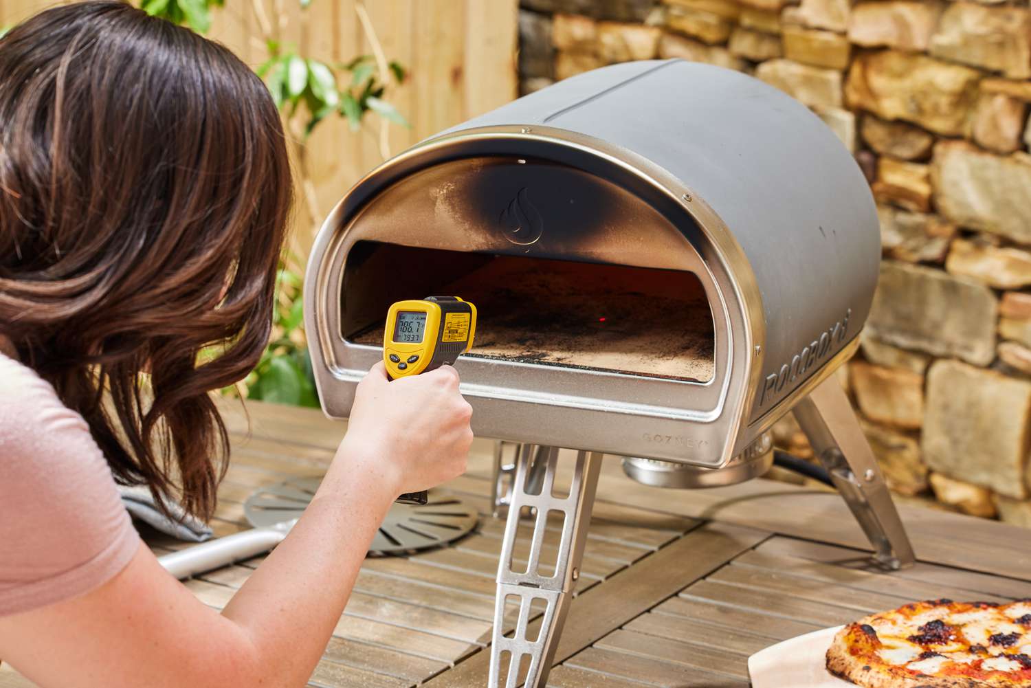 A person using a temperature reader on the Gozney Roccbox Pizza Oven