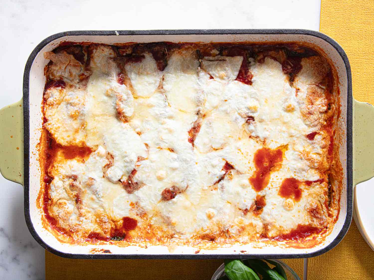 A baked dish of zucchini parmesan with cheese and sauce in a rectangular pan