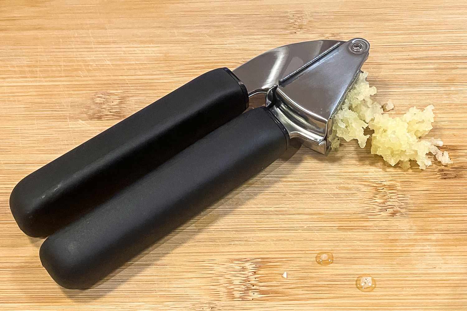 Garlic press with minced garlic on a wooden surface