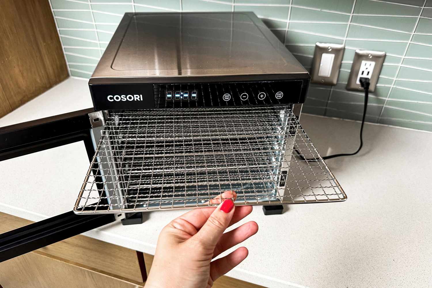 A person pulling out the racks of the Cosori food dehydrator