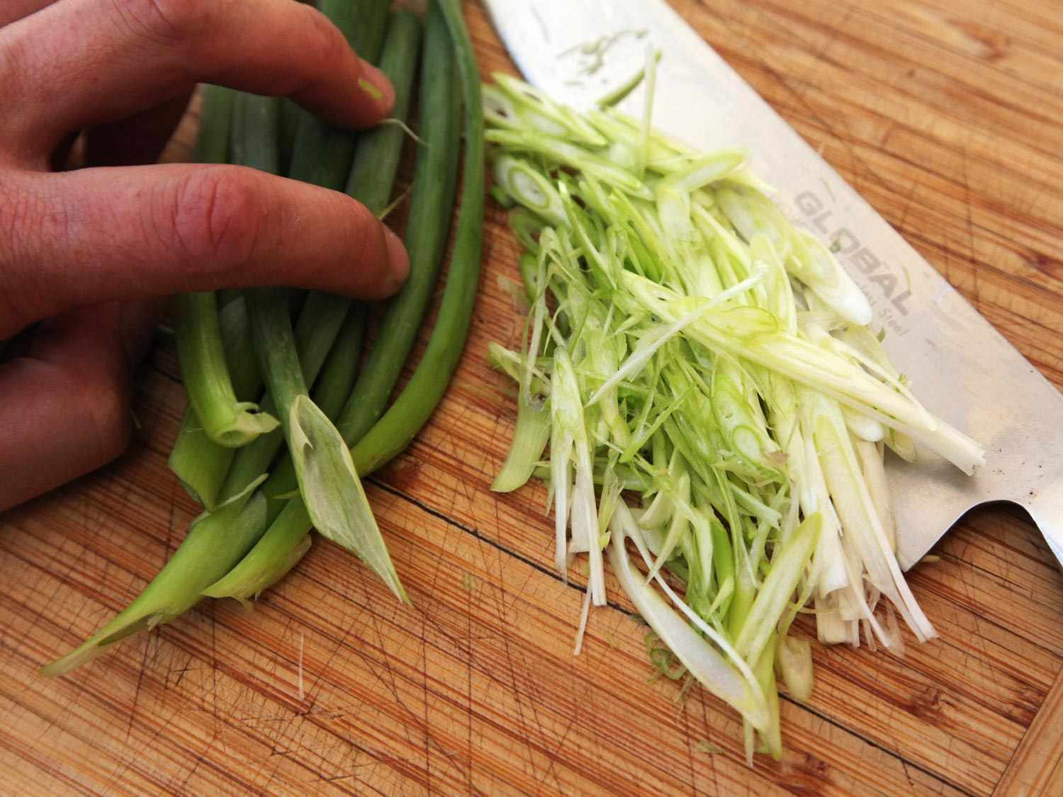 Fine strips of scallion on a cutting board.