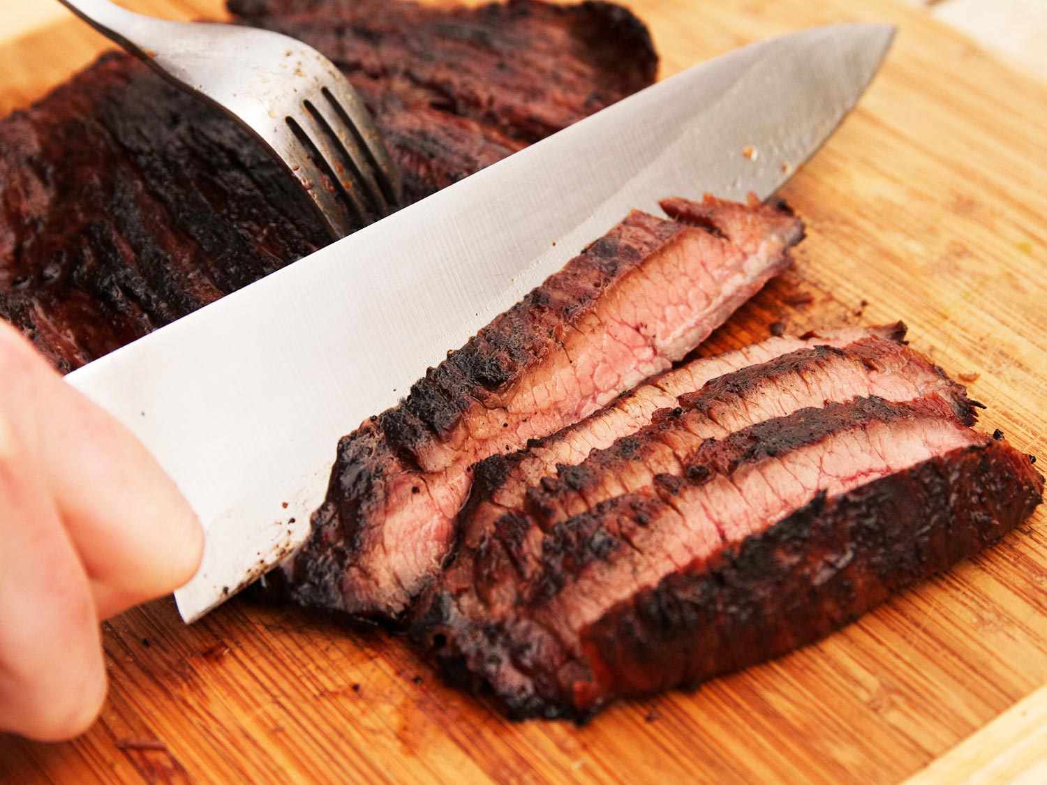 Slicing up a steak with a large chef's knife and fork.