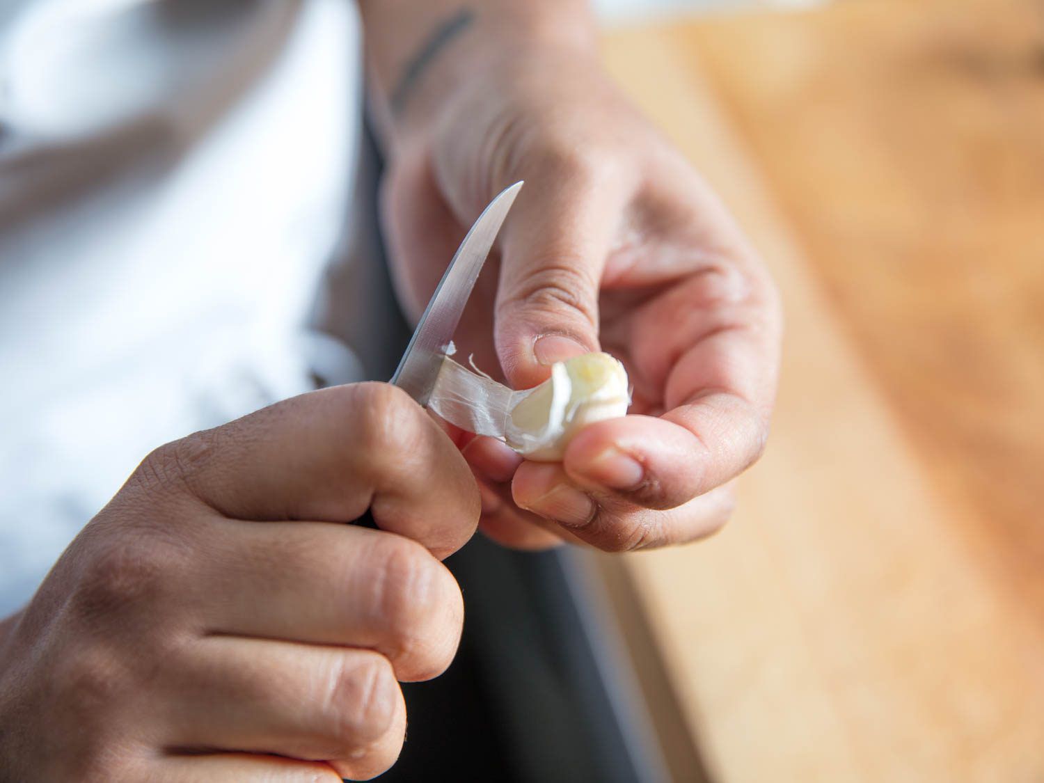 Author peels a garlic clove with a tourné knife.