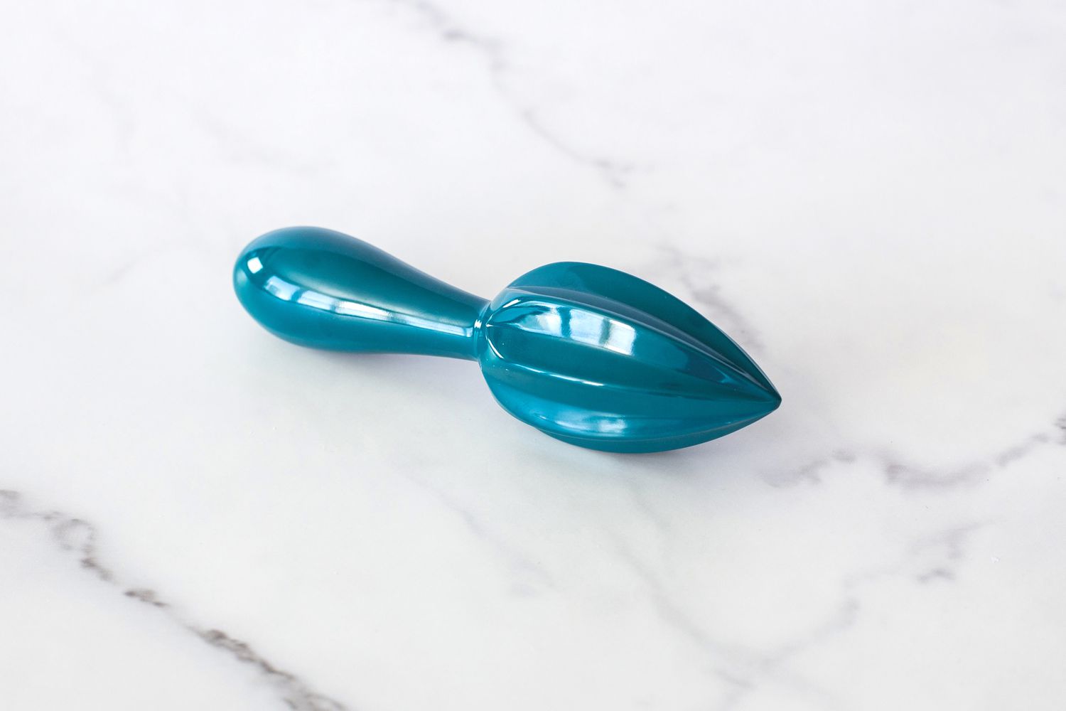 A blue ZAK! Handheld Citrus Reamer on a white counter.