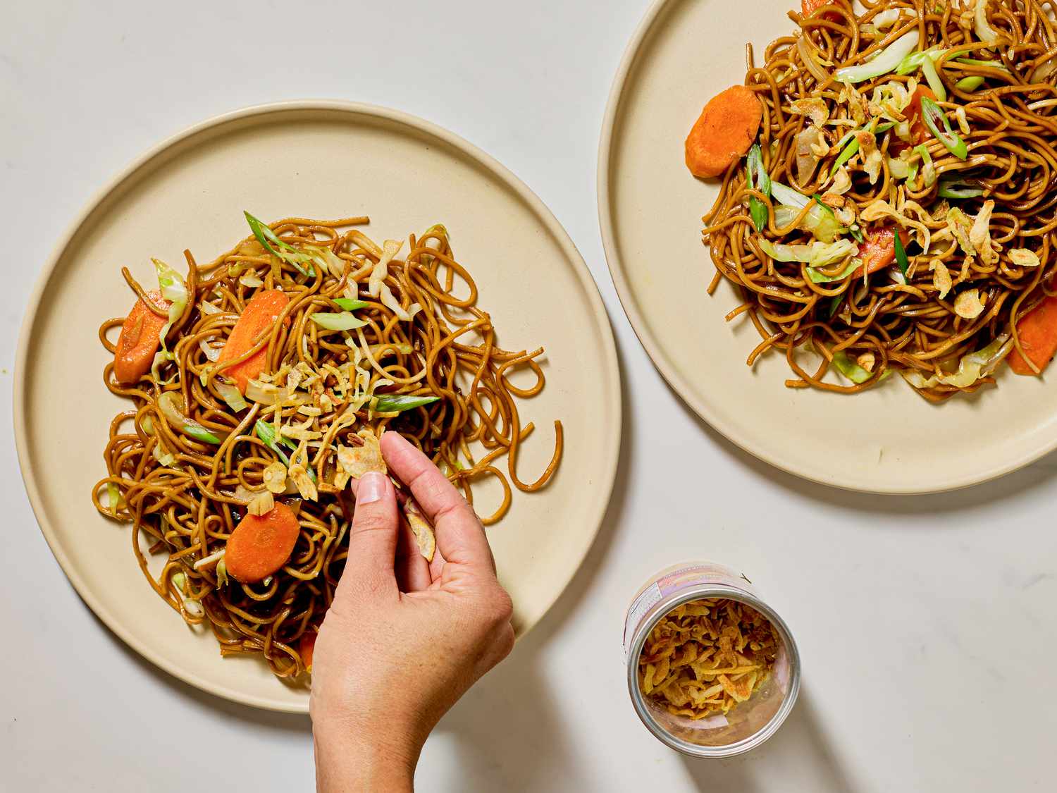 Garnishing noodles with fried shallots.