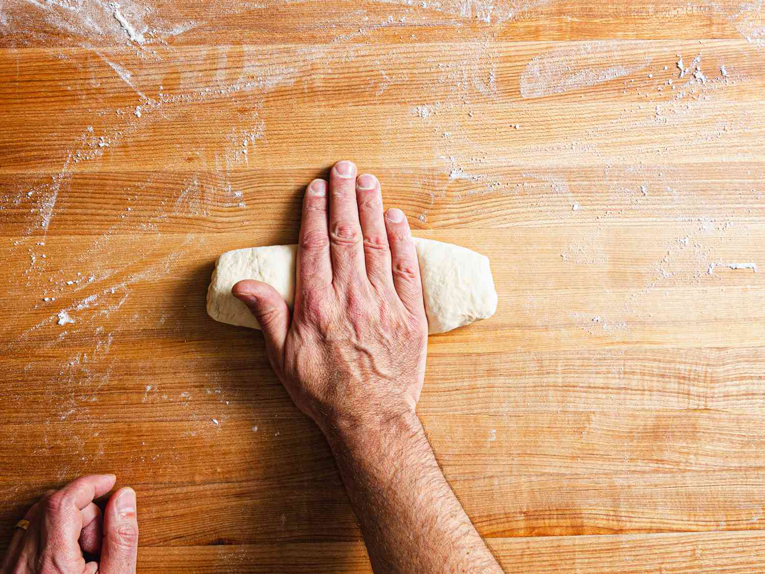 A hand gently pressing down on the dough 