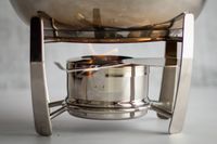 A stainless steel fondue pot with a flame underneath it. 
