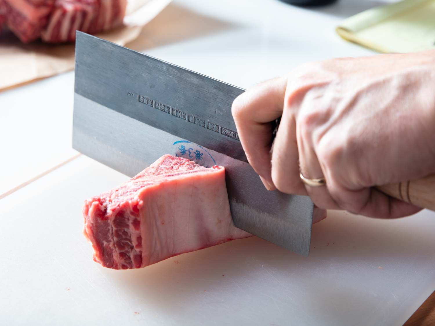 Using a cleaver to split beef short ribs between the bones