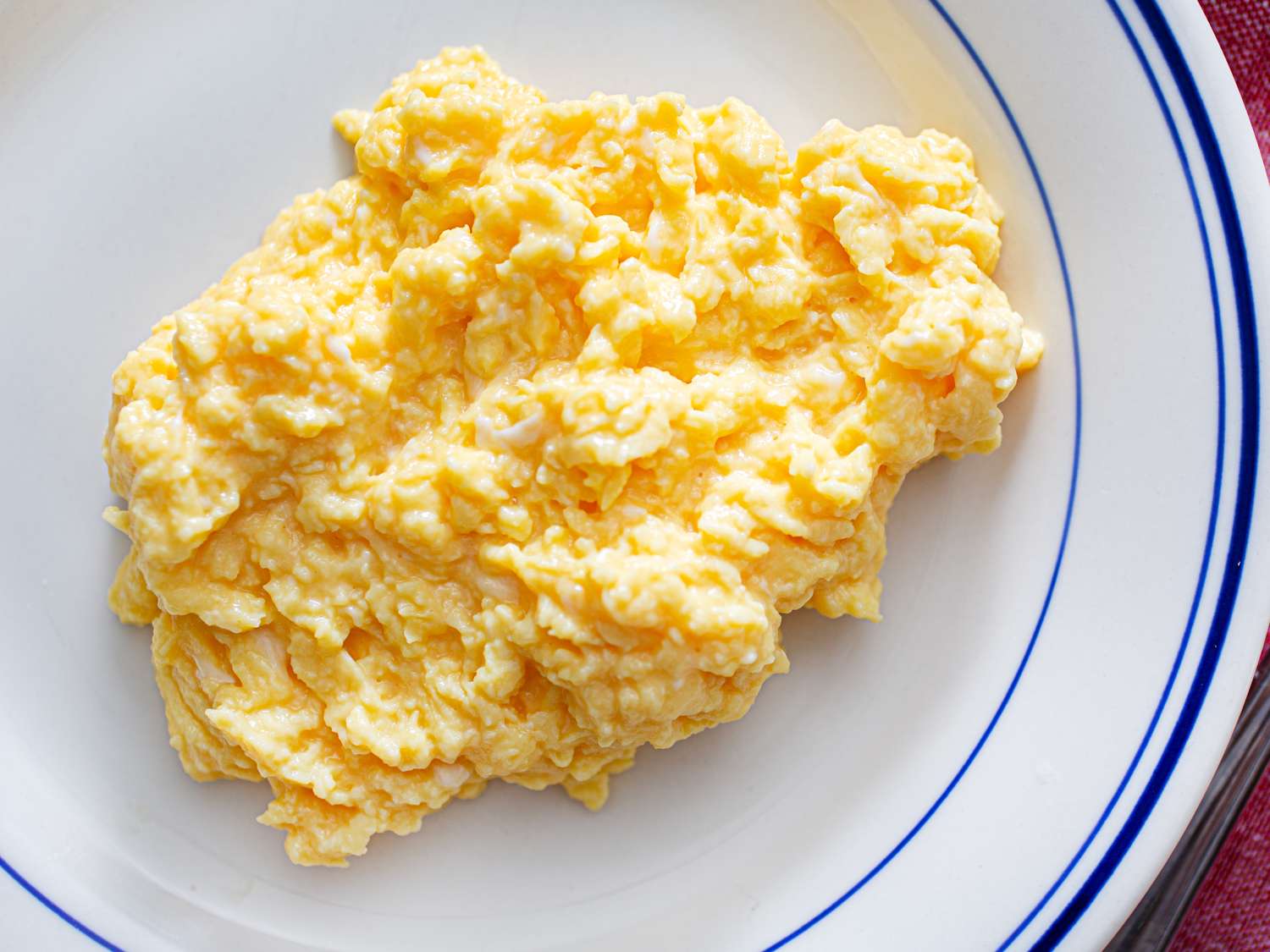 Scrambled eggs served on a white plate with a blue trim