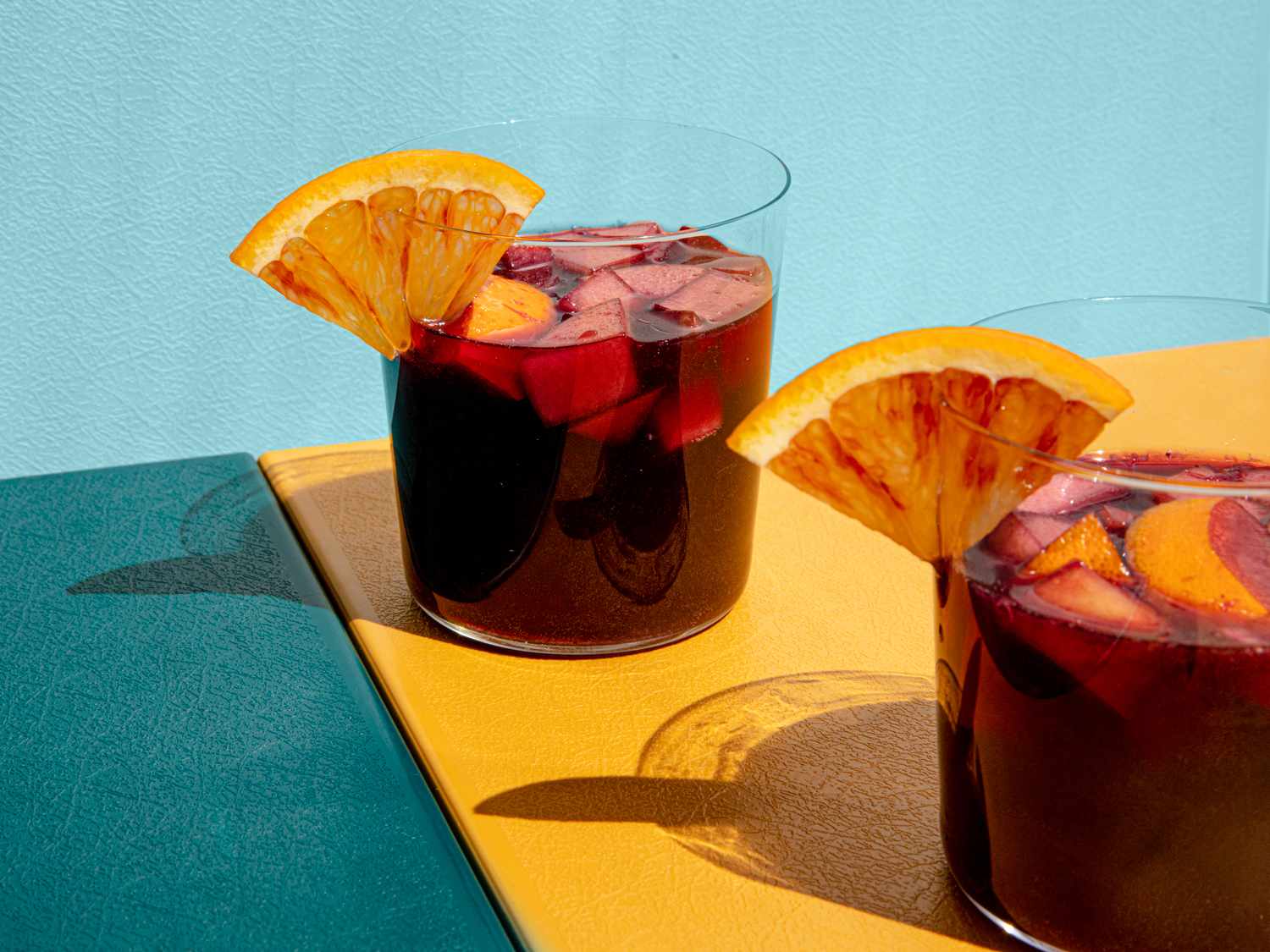 Two glasses of sangria adorned with orange wedges.