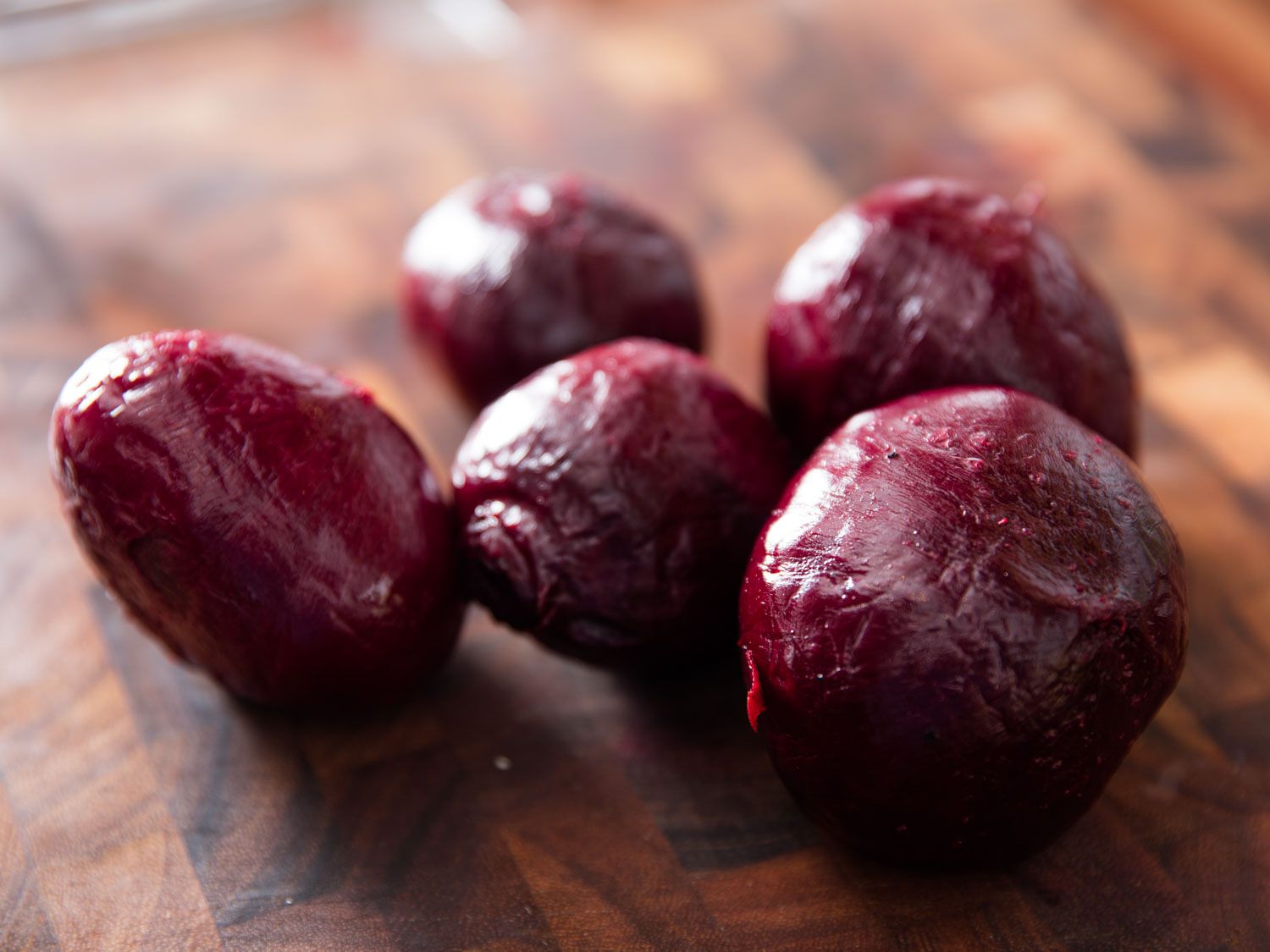 Peeled roasted beets on a wooden cutting board.